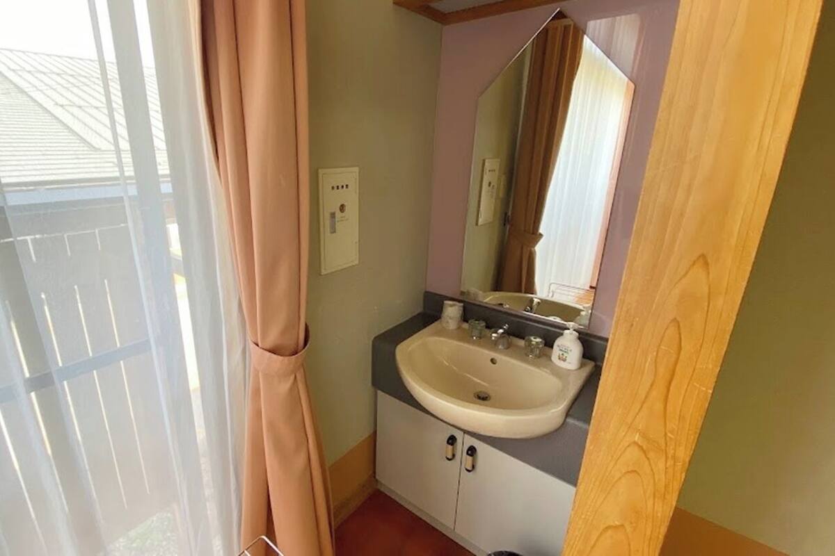 A bathroom with a sink, mirror, and window with curtains.
