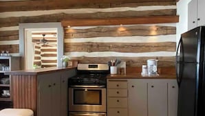 A kitchen with wooden wall paneling, stainless steel appliances, and a wooden countertop.