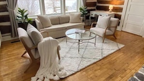 A cozy living room with a sofa, two armchairs, a coffee table, and a rug.