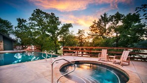 A pool area with a hot tub, lounge chairs, and a wooden deck.