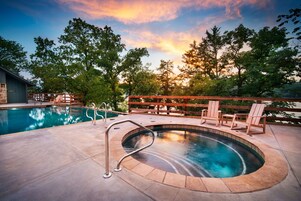 A pool area with a hot tub, lounge chairs, and a wooden deck.