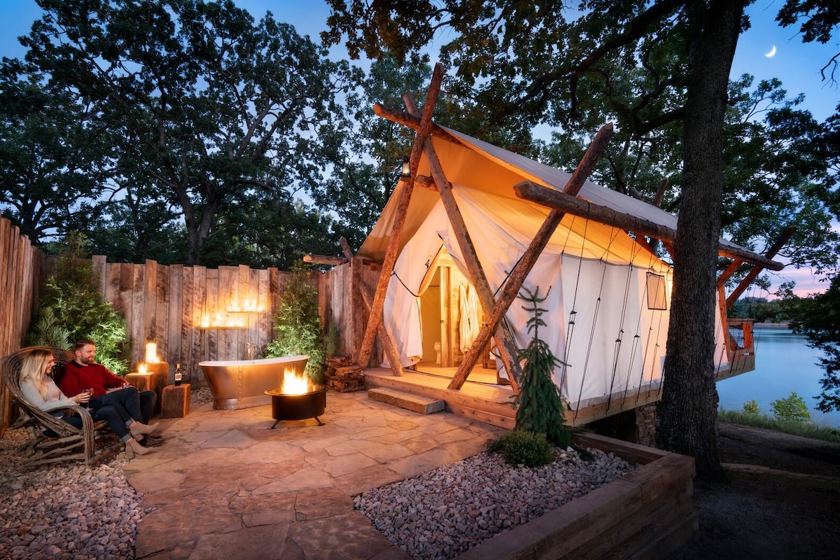 A cozy outdoor cabin with a stone patio, a hot tub, and a fire pit.