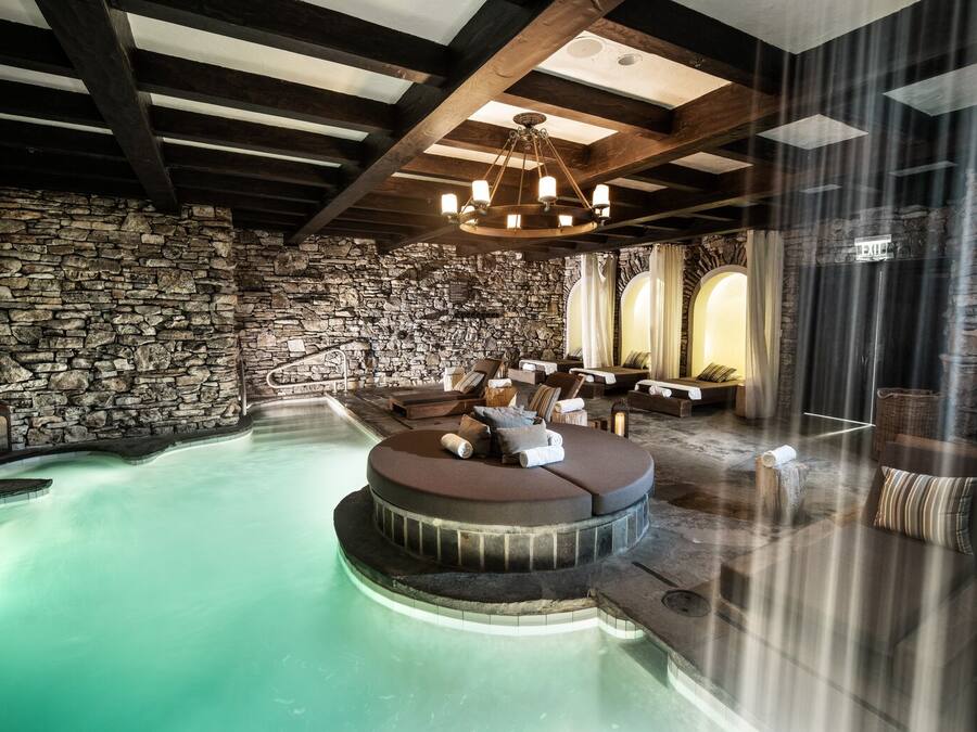 A spa area with a stone wall, a circular hot tub, and several lounge chairs.