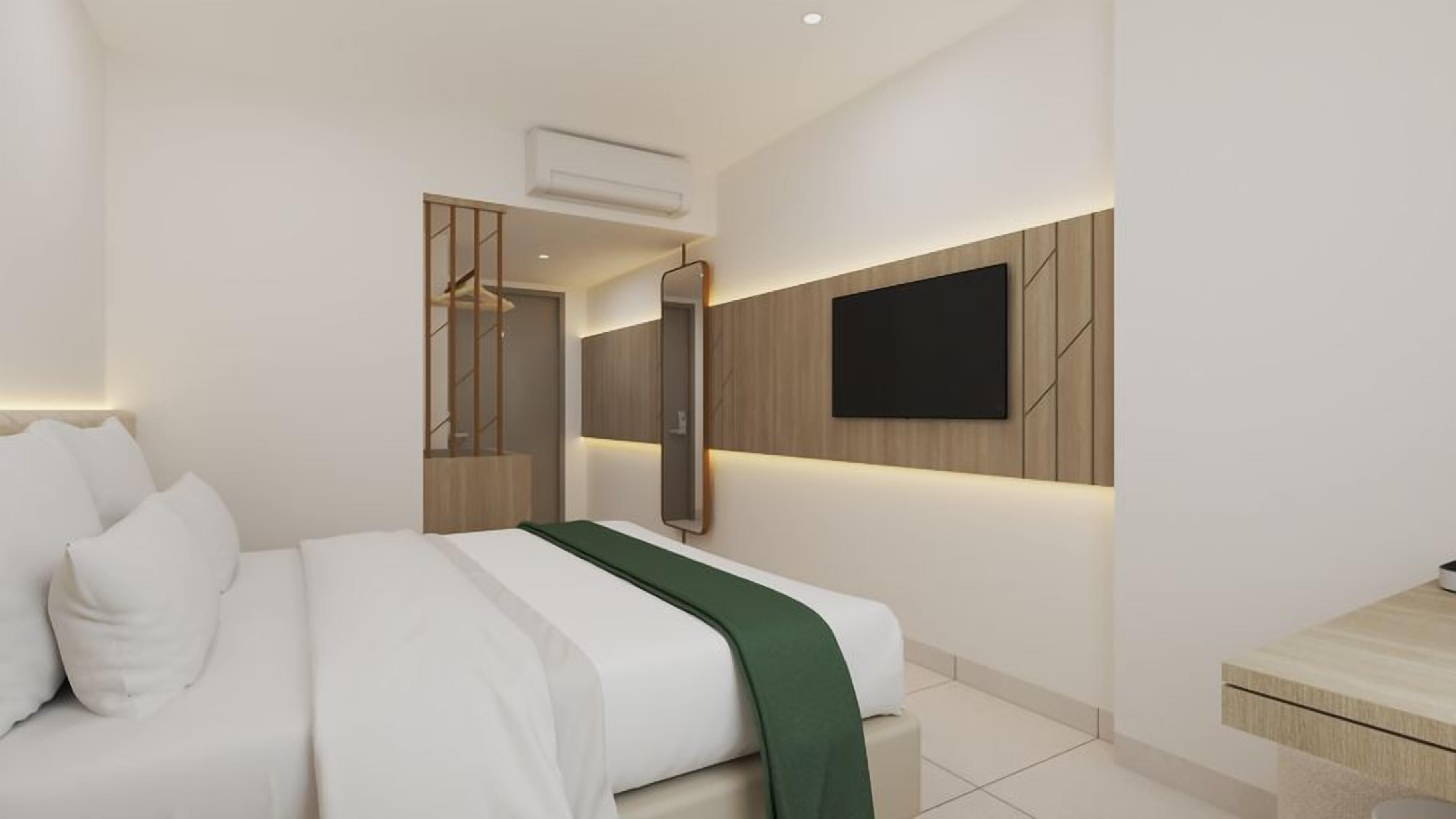 Une chambre d’hôtel moderne, équipée d’un lit, d’un téléviseur fixé au mur et d’un miroir.