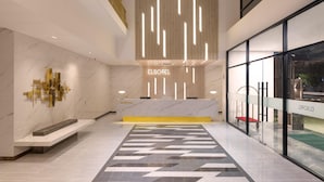 Un área de recepción moderna de hotel con un mostrador de mármol y un mostrador con una placa de identificación, además de un piso con diseño.