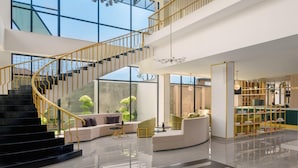 Un interior amplio con escalera, zona de estar y mostrador de recepción.