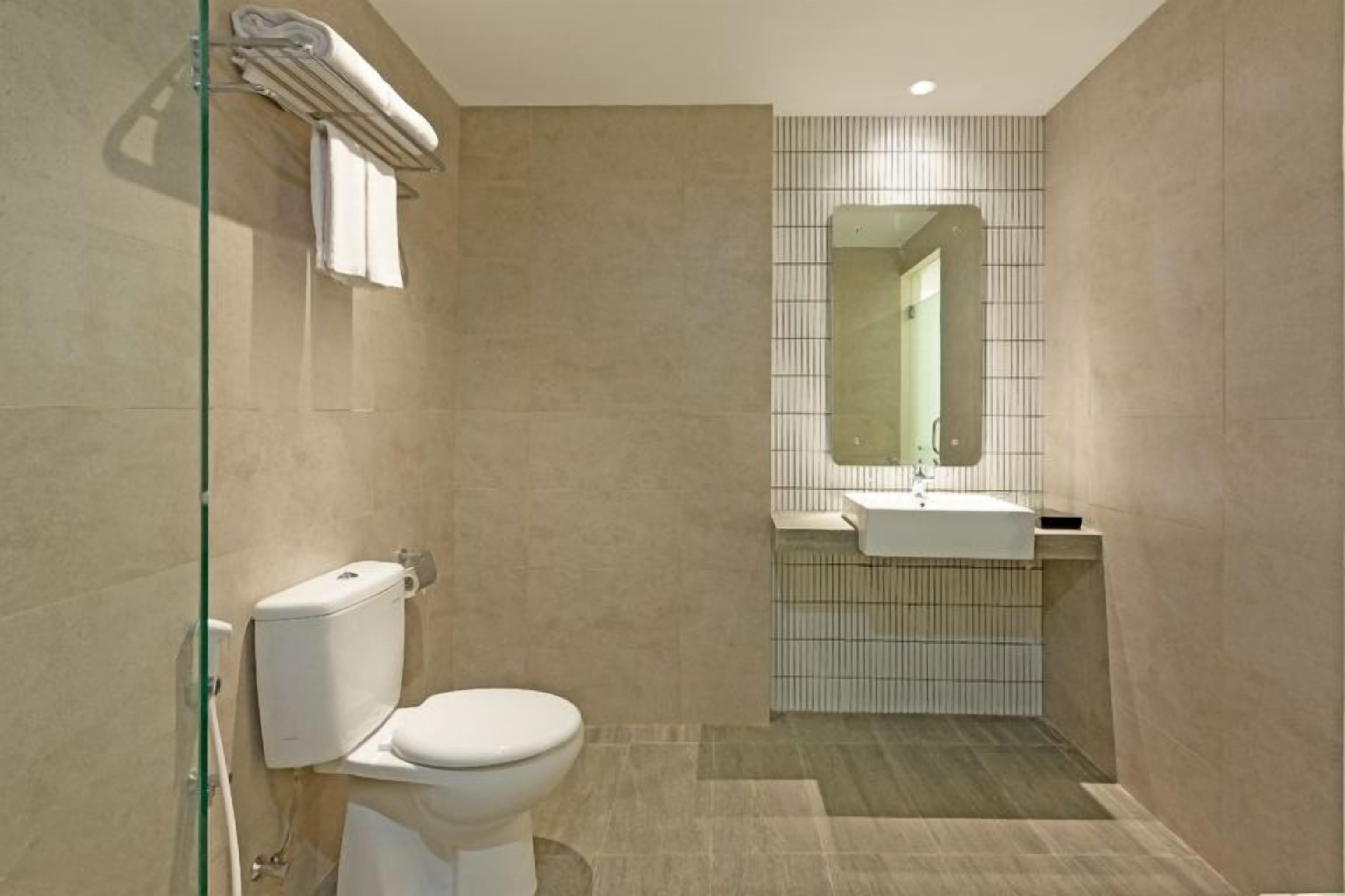 A bathroom with a toilet, sink, and mirror.
