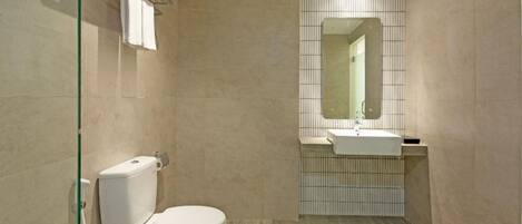 A bathroom with a toilet, sink, and mirror.