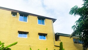A yellow brick building with multiple windows and a visible balcony. - Hôtel La Rochelle  (Bonaberi)