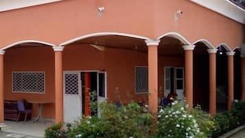 Un bâtiment doté d’un espace extérieur abrité, de climatiseurs et d’un petit jardin fleuri.