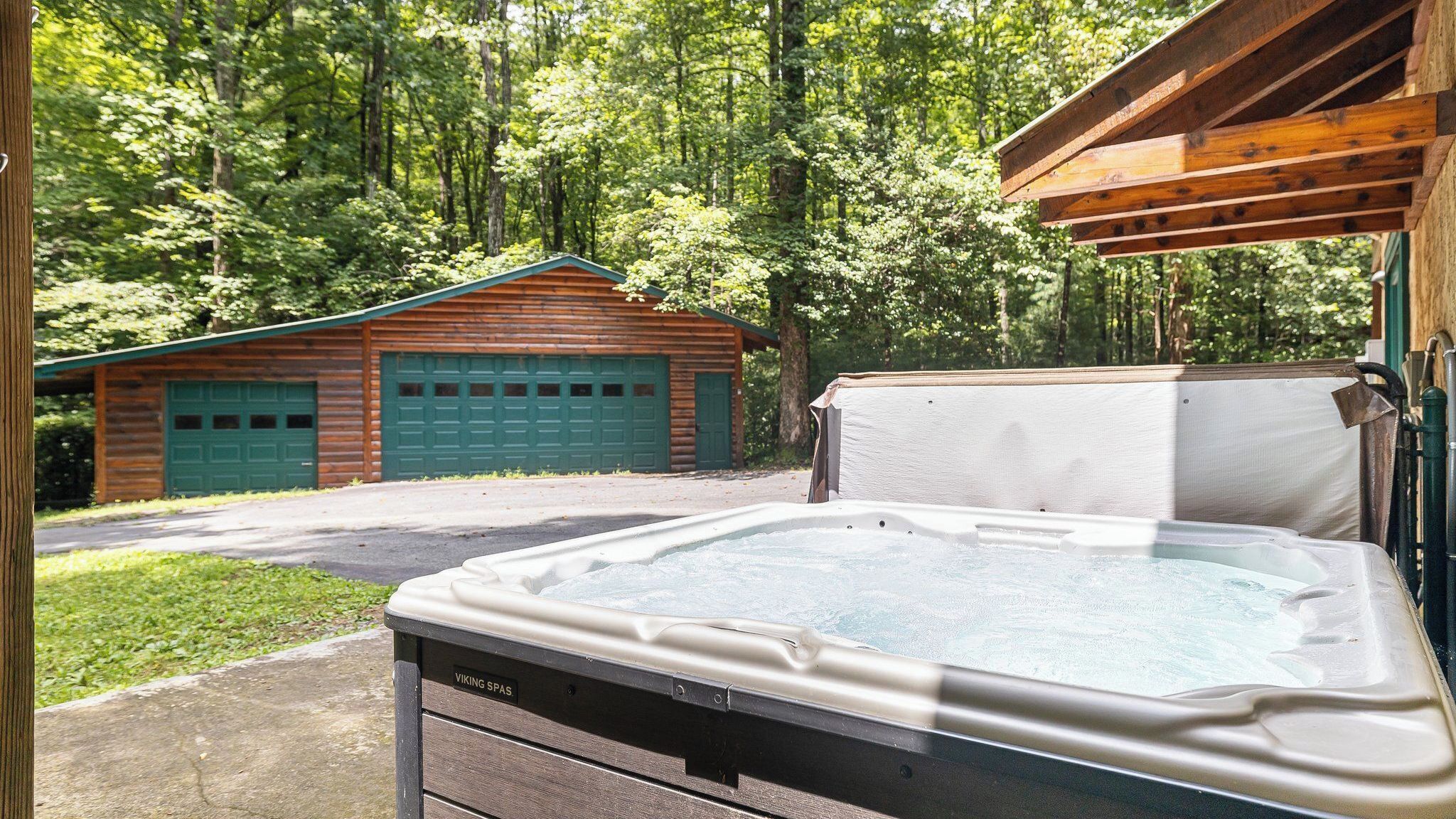 Un jacuzzi en un área boscosa, con una cabaña de madera al fondo.
