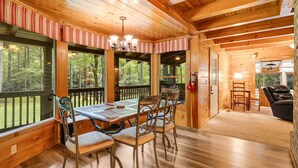 A wooden cabin interior with a dining table, chairs, and a fireplace. - Twin Creeks Lodge by Avantstay 33 Acre Retreat (Brevard)