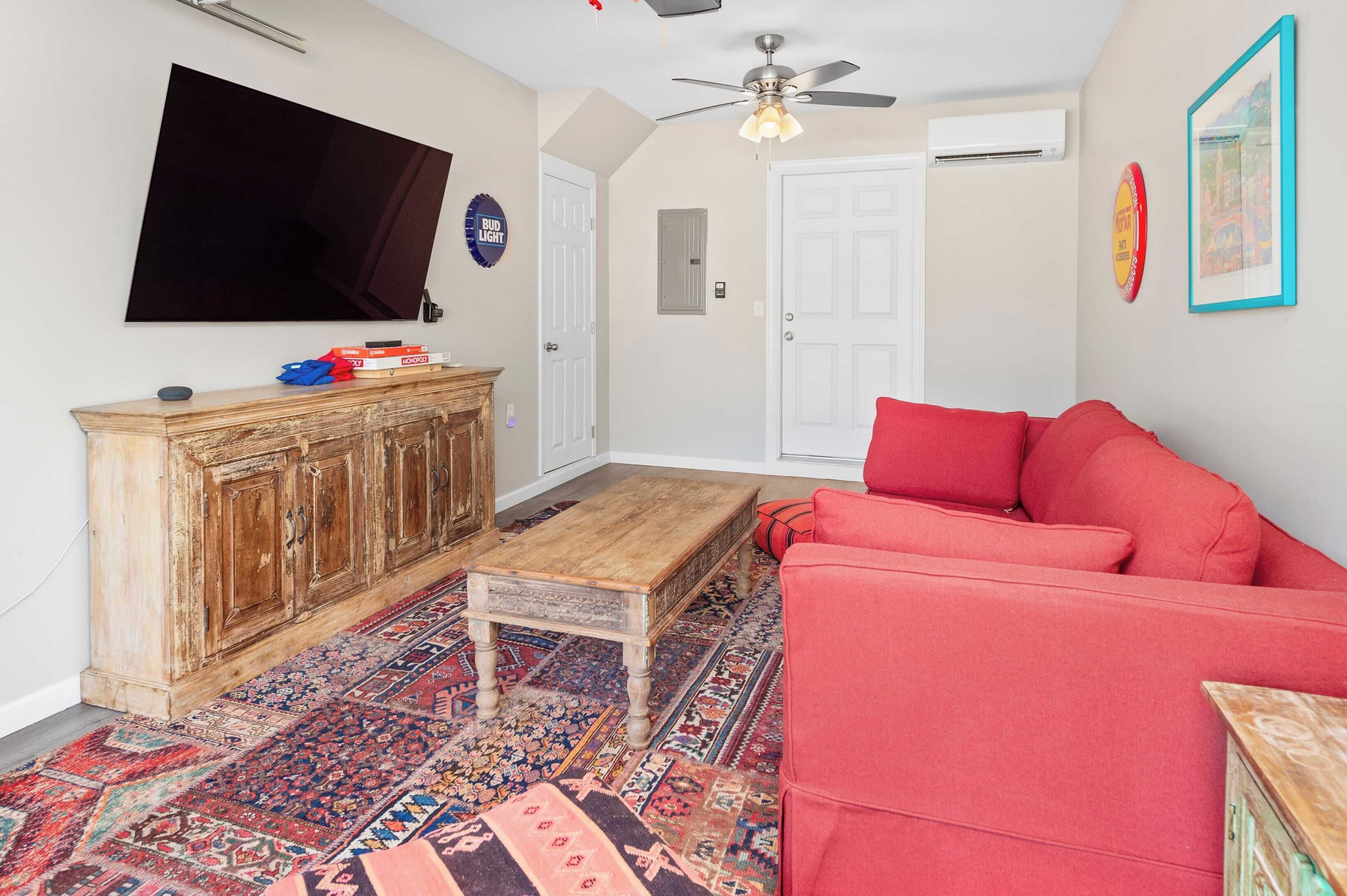 A living room with a red sofa, a wooden cabinet, a flat-screen TV, and a patterned rug.