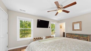 A bedroom with a bed, a ceiling fan, a TV, and a dresser. - Little Sycamore by Avantstay Premier Location + Patio (Asheville)