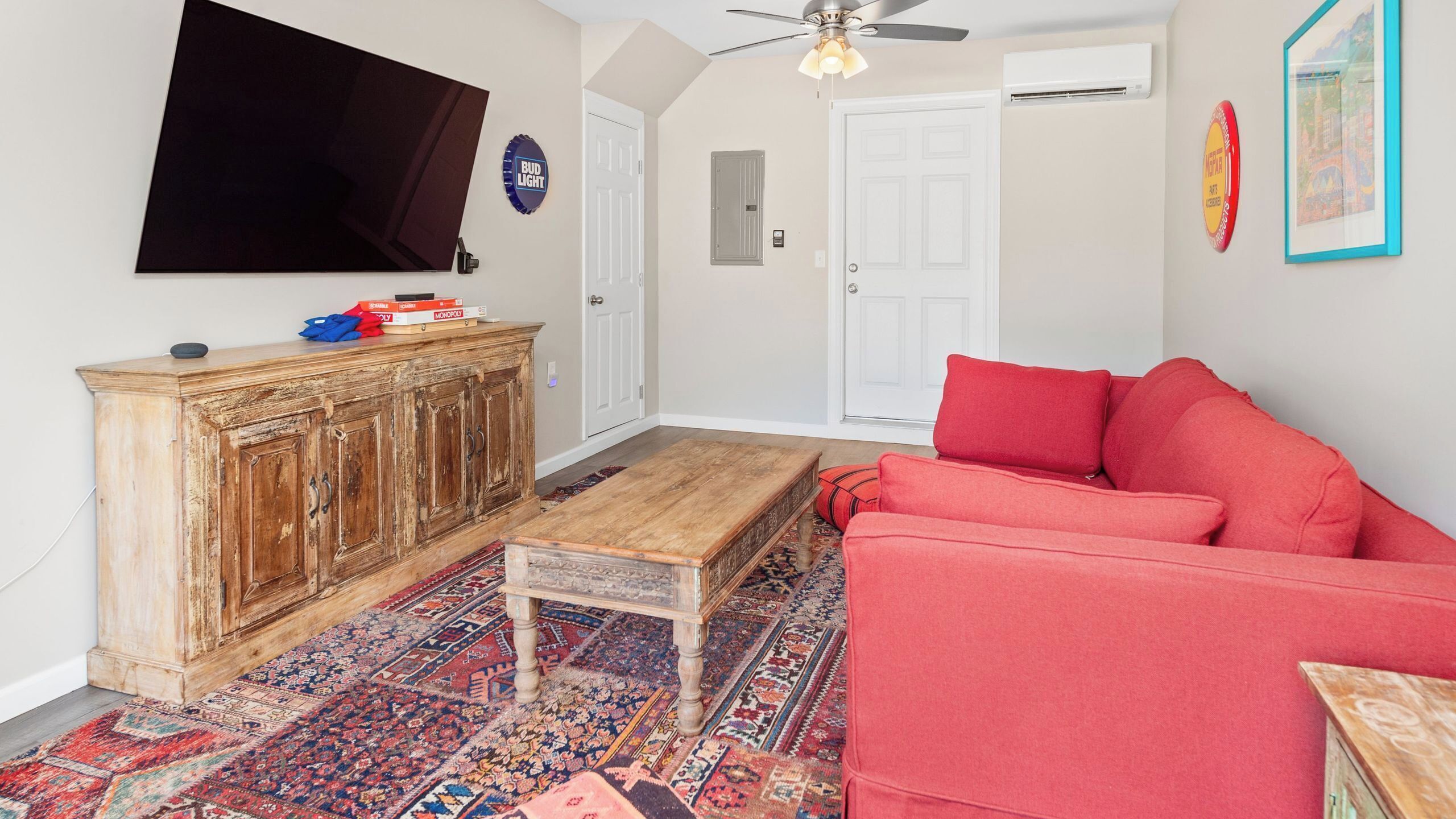 A living room with a red sofa, wooden cabinet, television, and patterned rug.