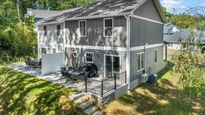 A two-story house with a covered patio, outdoor seating, and a grill. - Little Sycamore by Avantstay Premier Location + Patio (Asheville)