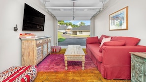 A compact living space with a red sofa, a coffee table, a TV mounted on the wall, and a colorful rug.