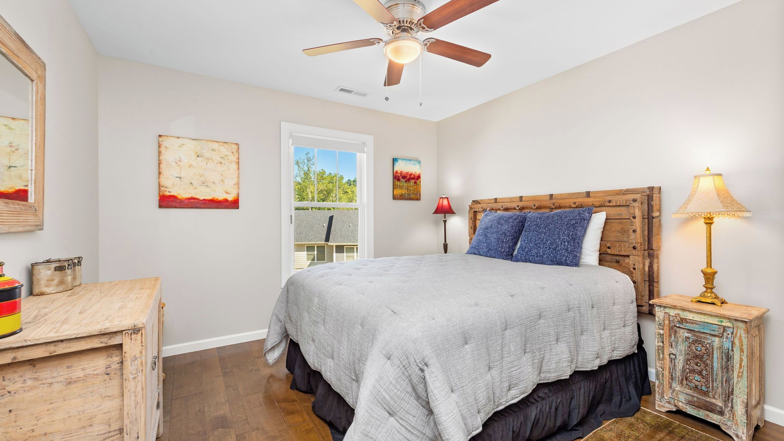 A bedroom with a bed, a ceiling fan, a window, and a door.