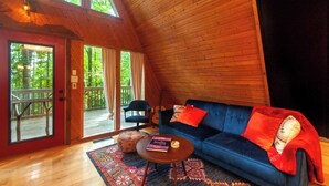 A cozy cabin interior with a blue sofa, a guitar, and a wooden ceiling. - Firepit + Mountain Views A-frame in Fairview Honeycomb Hideaway by Avantstay (Fairview)