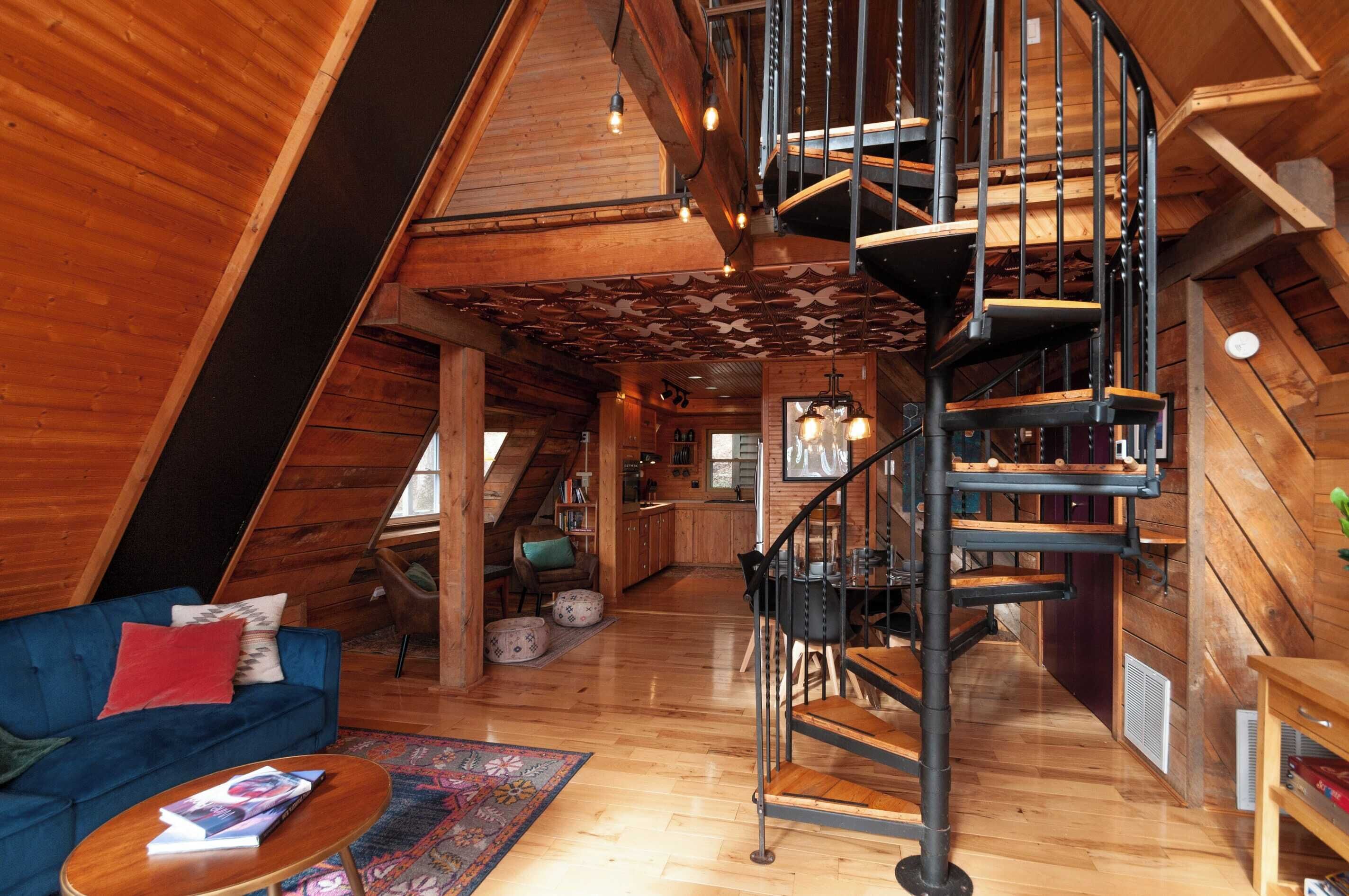 Ein Holzinnenraum mit einer Wendeltreppe, einem blauen Sofa und einem Essbereich.