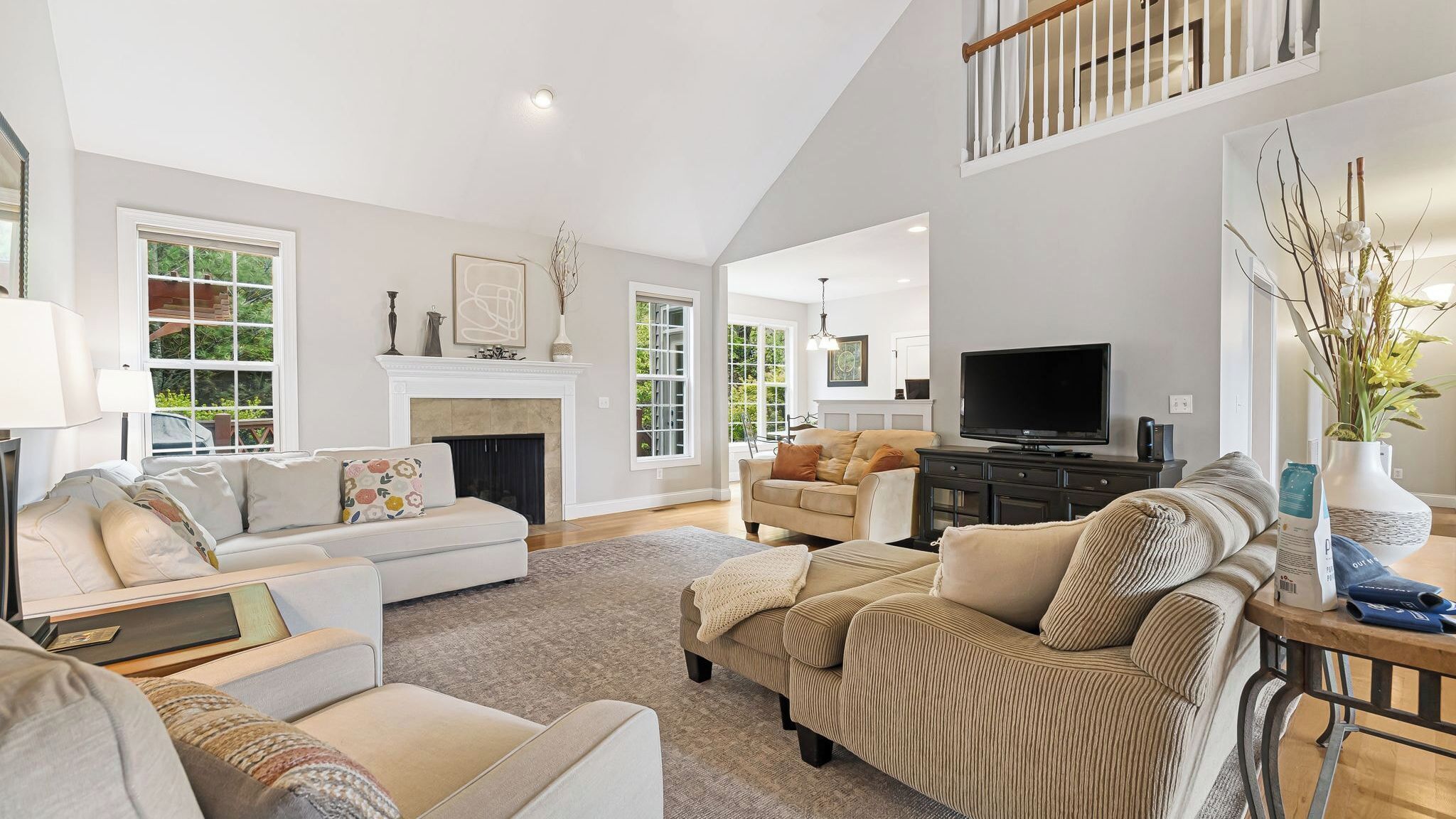 A spacious living room with a fireplace, a television, and a high ceiling.