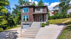 A modern two-story house with a front entrance, a staircase, and a driveway.