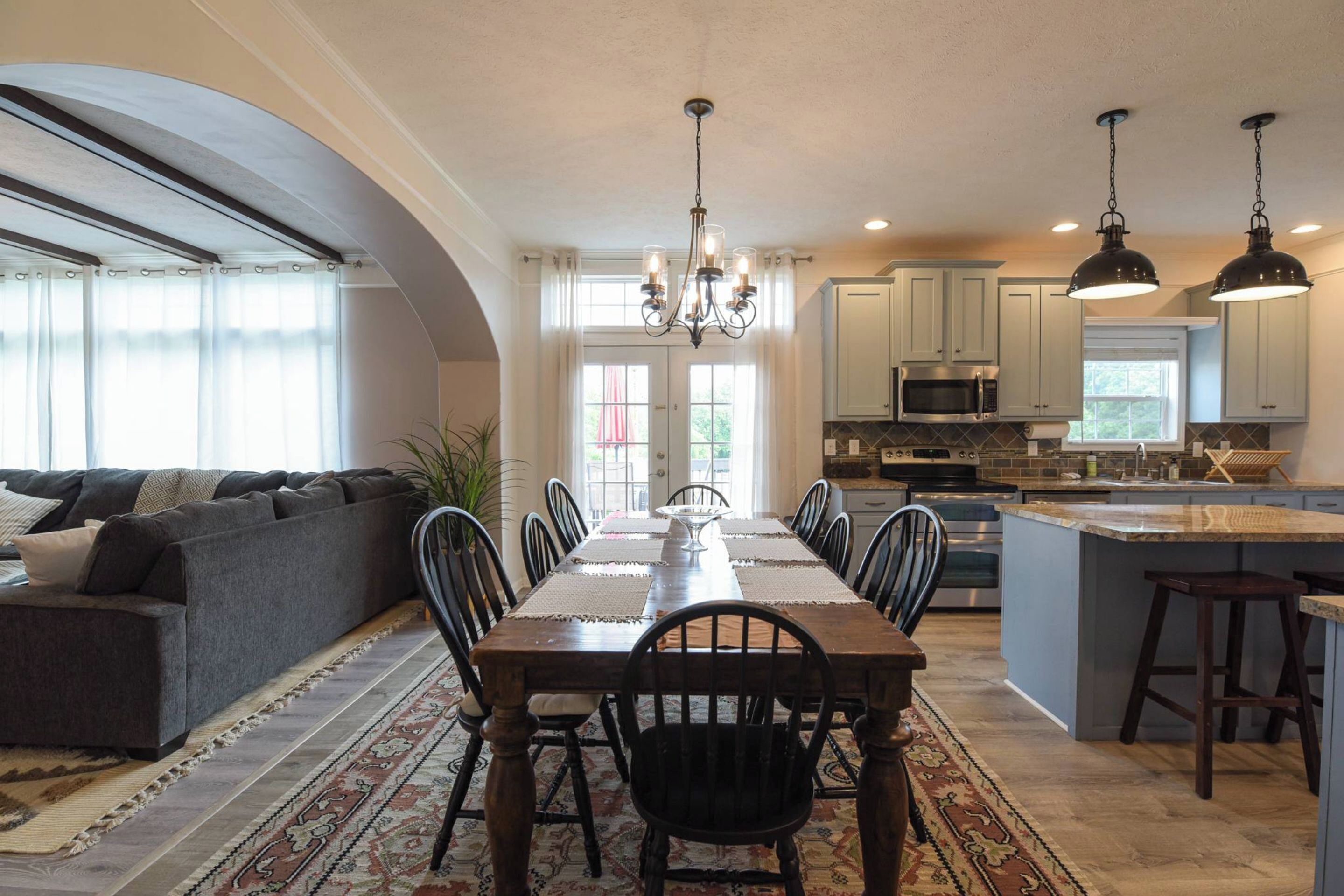 A spacious kitchen with a dining area, featuring a chandelier, island, and modern appliances.