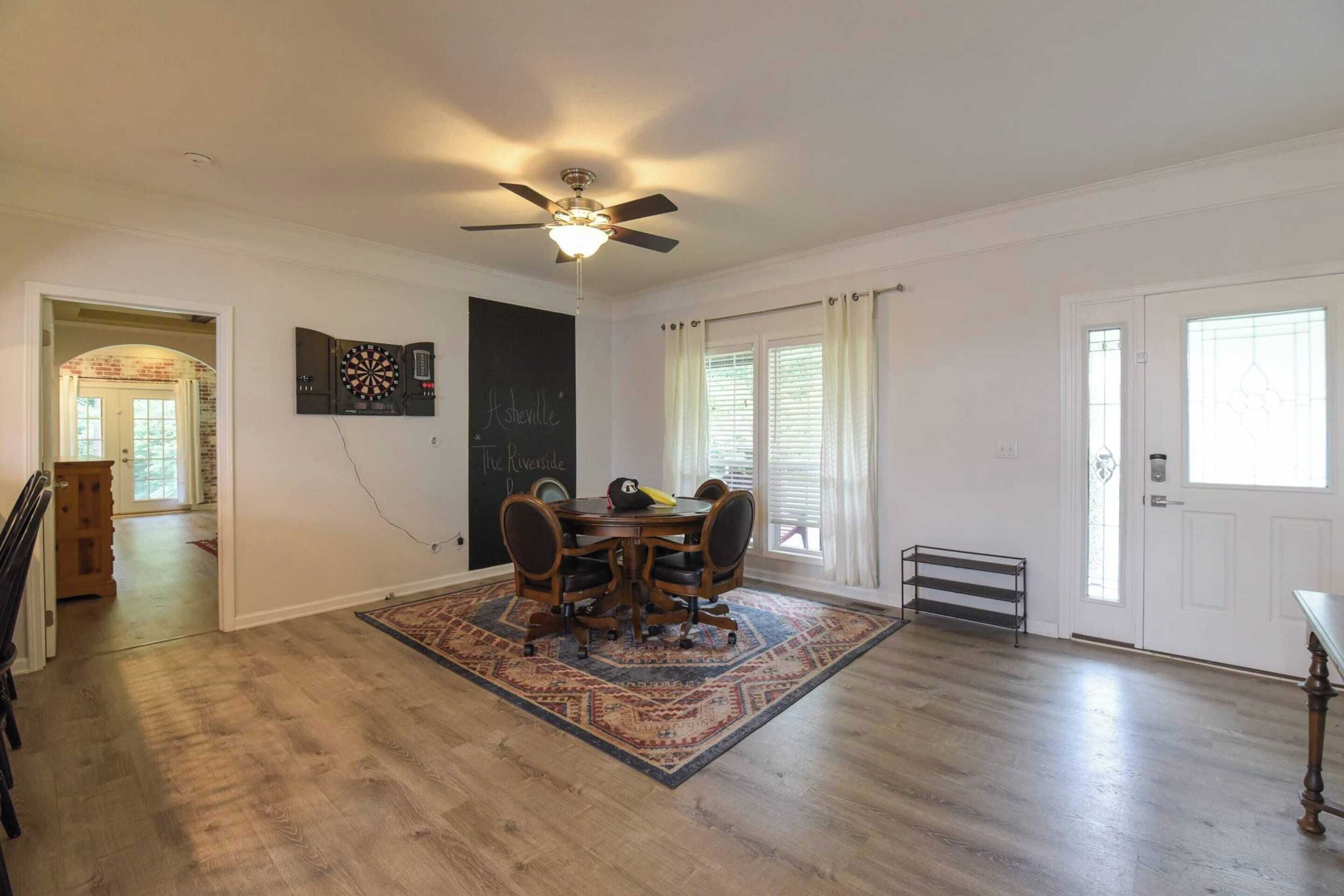 Un coin repas avec une table ronde, quatre chaises, un ventilateur de plafond et un tapis à motifs.