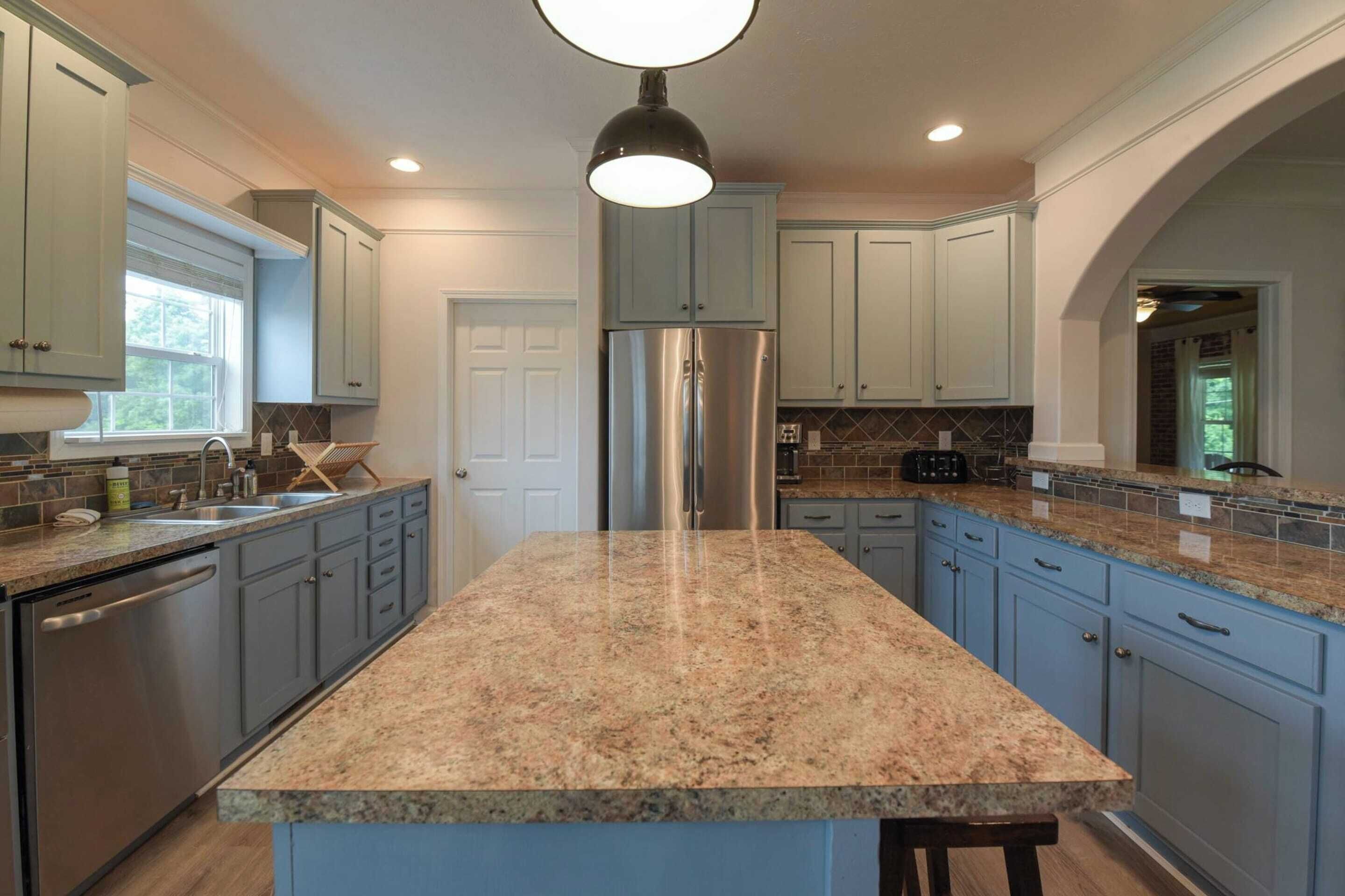 A kitchen with granite countertops, stainless steel appliances, and light blue cabinetry.