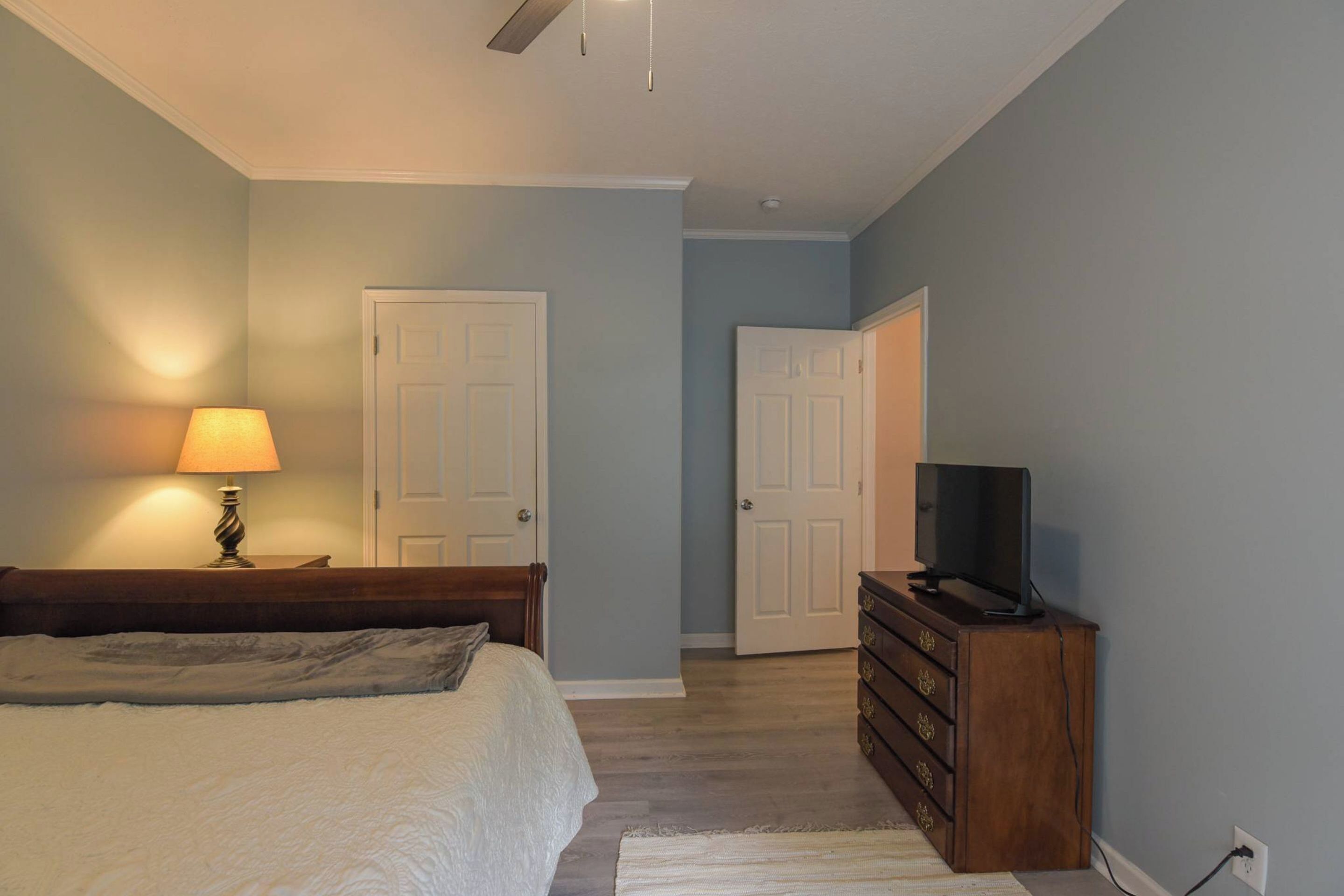 Une chambre à coucher comprenant un lit, une commode, un téléviseur et deux portes.