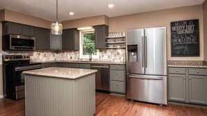 A modern kitchen with granite countertops, stainless steel appliances, and a large island.