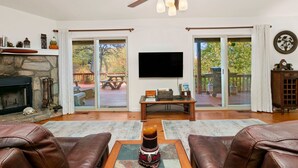Ein Wohnzimmer mit Kamin, Ledersofas, Fernseher und Deckenventilator.