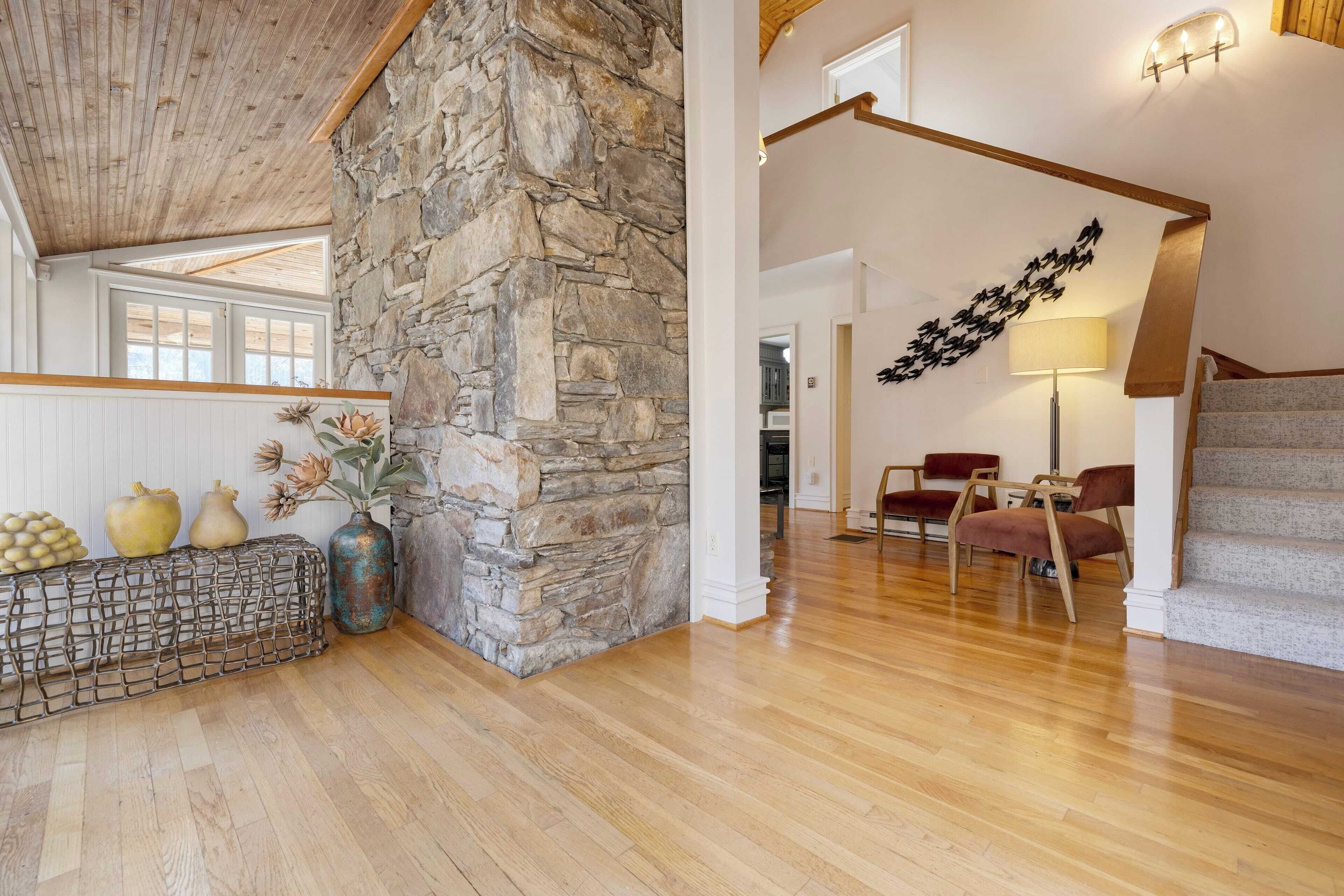 A spacious room with a stone wall, wooden ceiling, and a staircase.