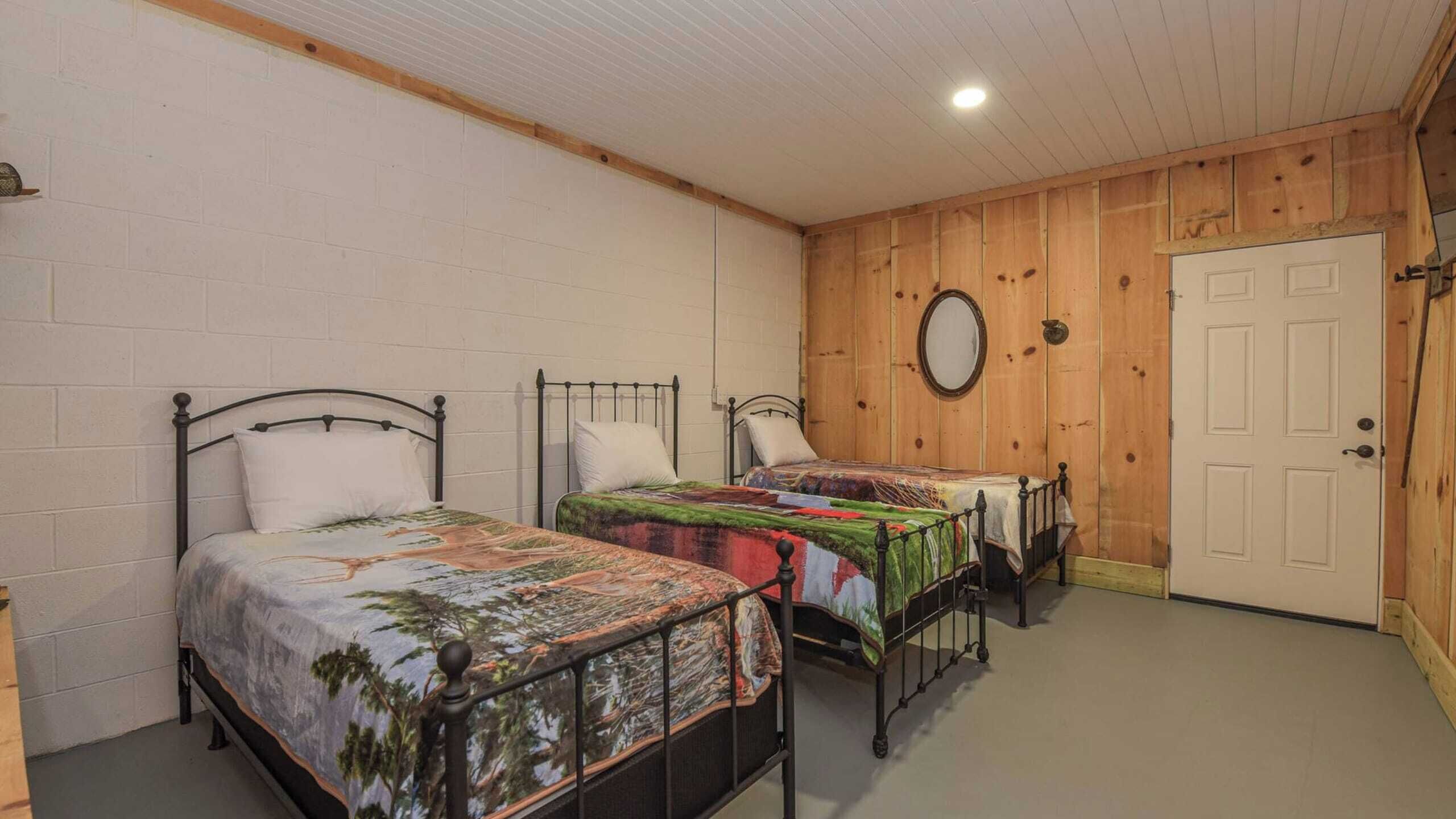 A room with two metal-framed beds, a white door, and wooden walls.