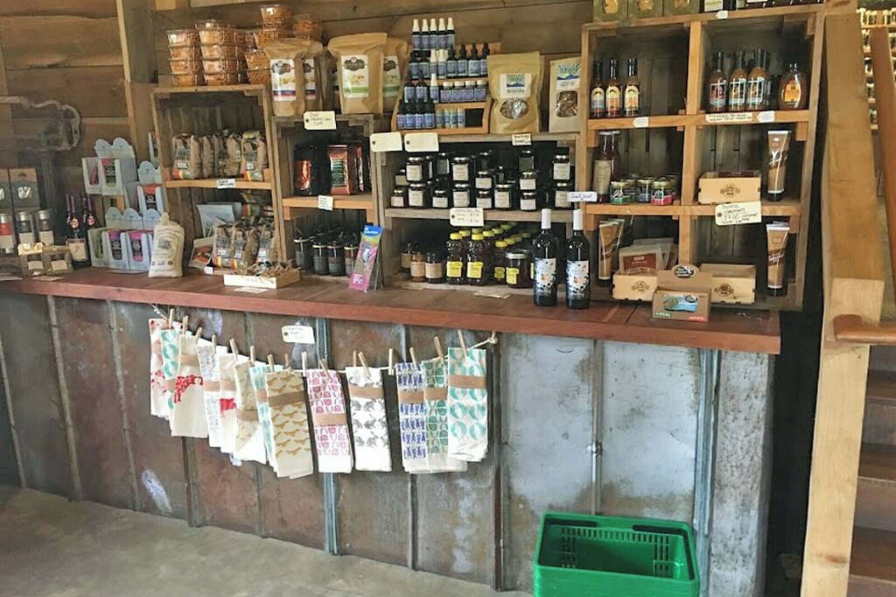 L’intérieur d’une boutique au style rustique, avec des étagères remplies de divers produits, un comptoir où sont exposés des articles, et des pinces à linge suspendues avec des petits disques en tissu.
