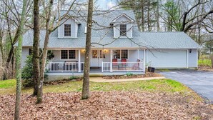 A two-story house with a porch, surrounded by trees. - Asheville Cottage Retreat by Avantstay A+ Charm (Fairview)