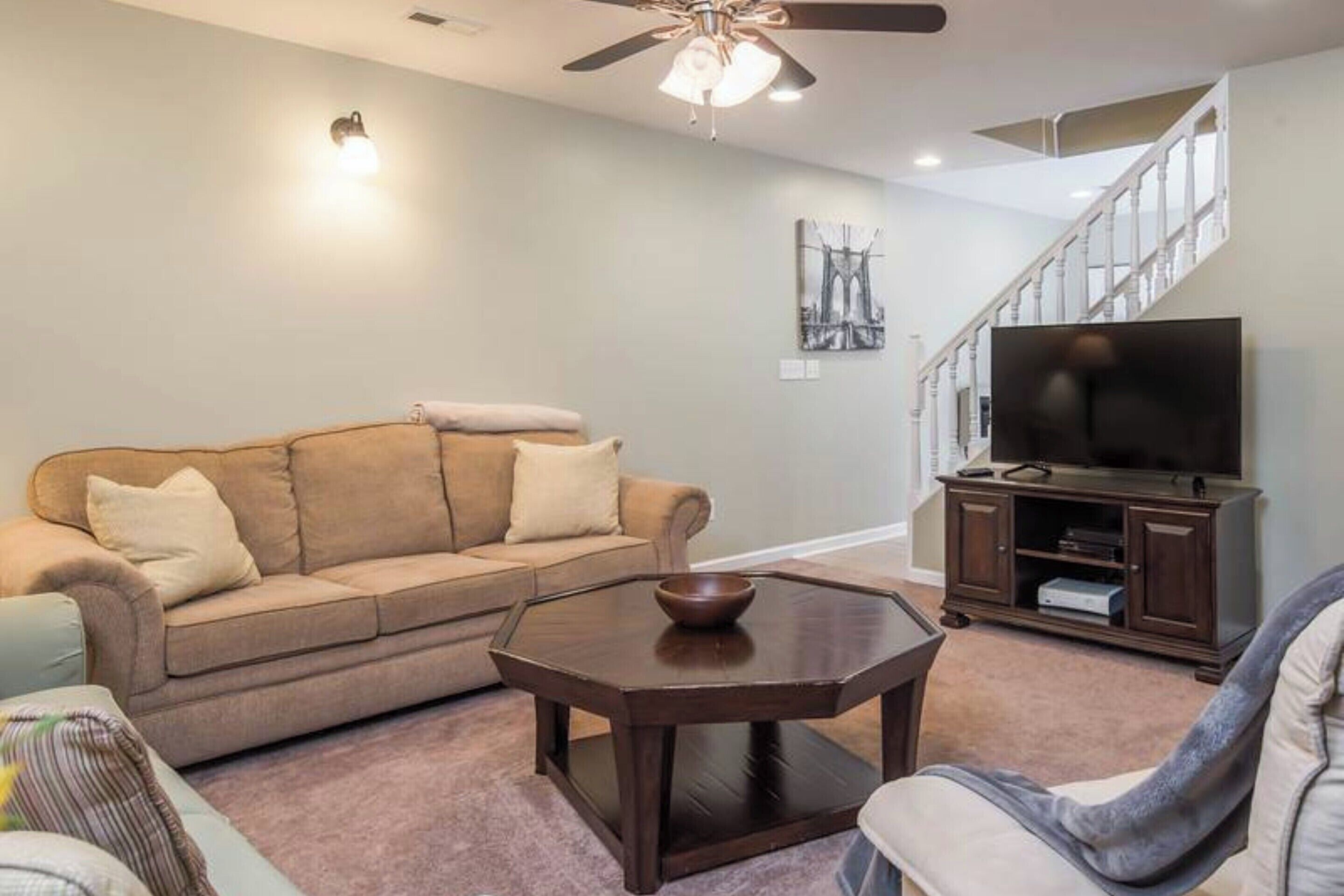 A living room with a sofa, a coffee table, a television, and a staircase.