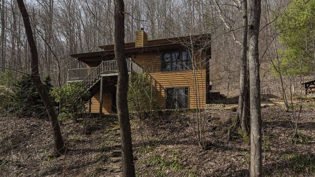 Eine Hütte mit Balkon, umgeben von Bäumen.