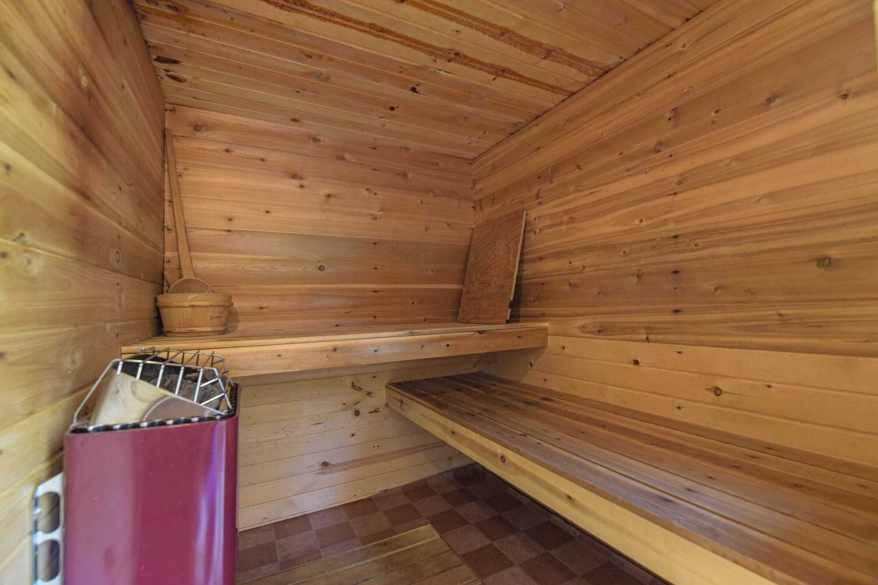 A sauna room with wooden walls and a bench.