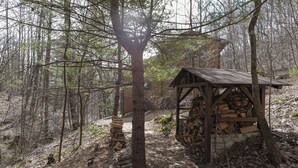 Eine rustikale Holzstruktur in einer bewaldeten Gegend mit einem Holzstapel.