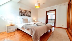 Camera da letto con un letto, comodini, una lampada, un quadro appeso e uno specchio.