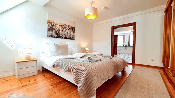 A bedroom with a bed, bedside tables, a lamp, a wall art piece, and a mirror.