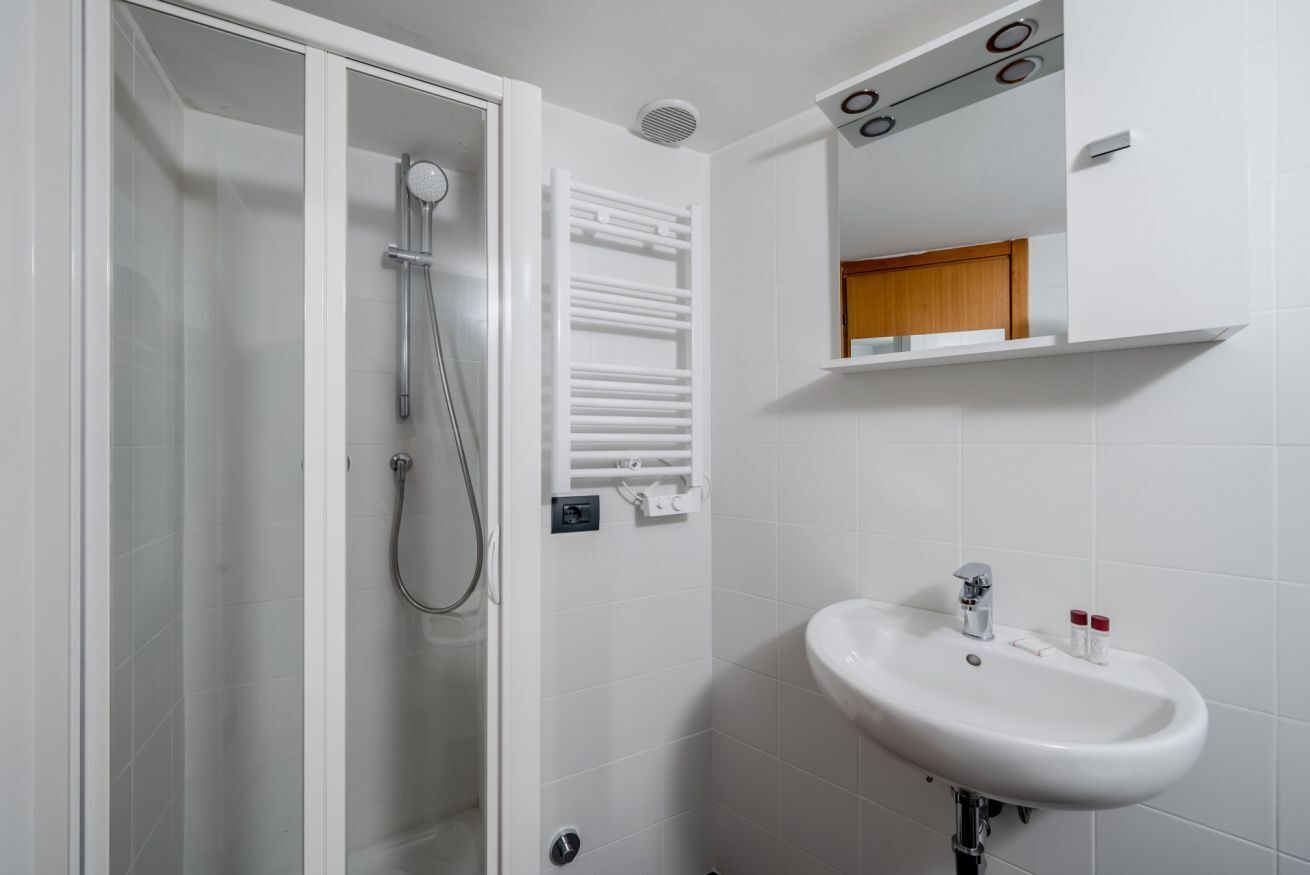 A bathroom with a shower, a sink, a towel rack, and a mirror.
