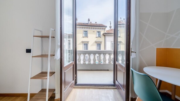 Uma varanda com vista para edifícios, uma cadeira branca e uma mesa.