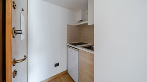 Uma cozinha compacta com lava-louças, pia e um armário sobre a bancada.
