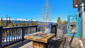 A wooden deck with a fire pit table, metal chairs, and a view of snow-capped mountains. - Cozy ski retreat in Breckenridge, Pet-friendly, unmatched view of Five peaks. (Breckenridge)