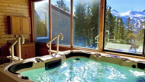 A hot tub with a view of snow-capped mountains through large windows. - Cozy ski retreat in Breckenridge, Pet-friendly, unmatched view of Five peaks. (Breckenridge)
