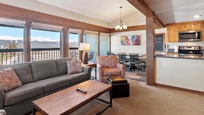 A modern living room with a sofa, armchair, and coffee table, a dining area with chairs, and a kitchen with a microwave. - Cozy ski retreat in Breckenridge, Pet-friendly, unmatched view of Five peaks. (Breckenridge)