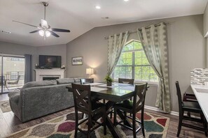 A living room with a sofa, dining table, chairs, a fireplace, and a ceiling fan.
