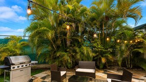 An outdoor patio with a grill, wicker furniture, and string lights. - Acogedora Casa con Excelente Ubicacion (Miami)
